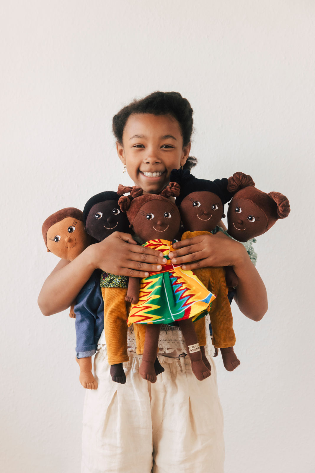 Ein schwarzes Mädchen hält eine Auswahl an Diversity-Puppen von LITTLE ASHÉ in den Händen 
