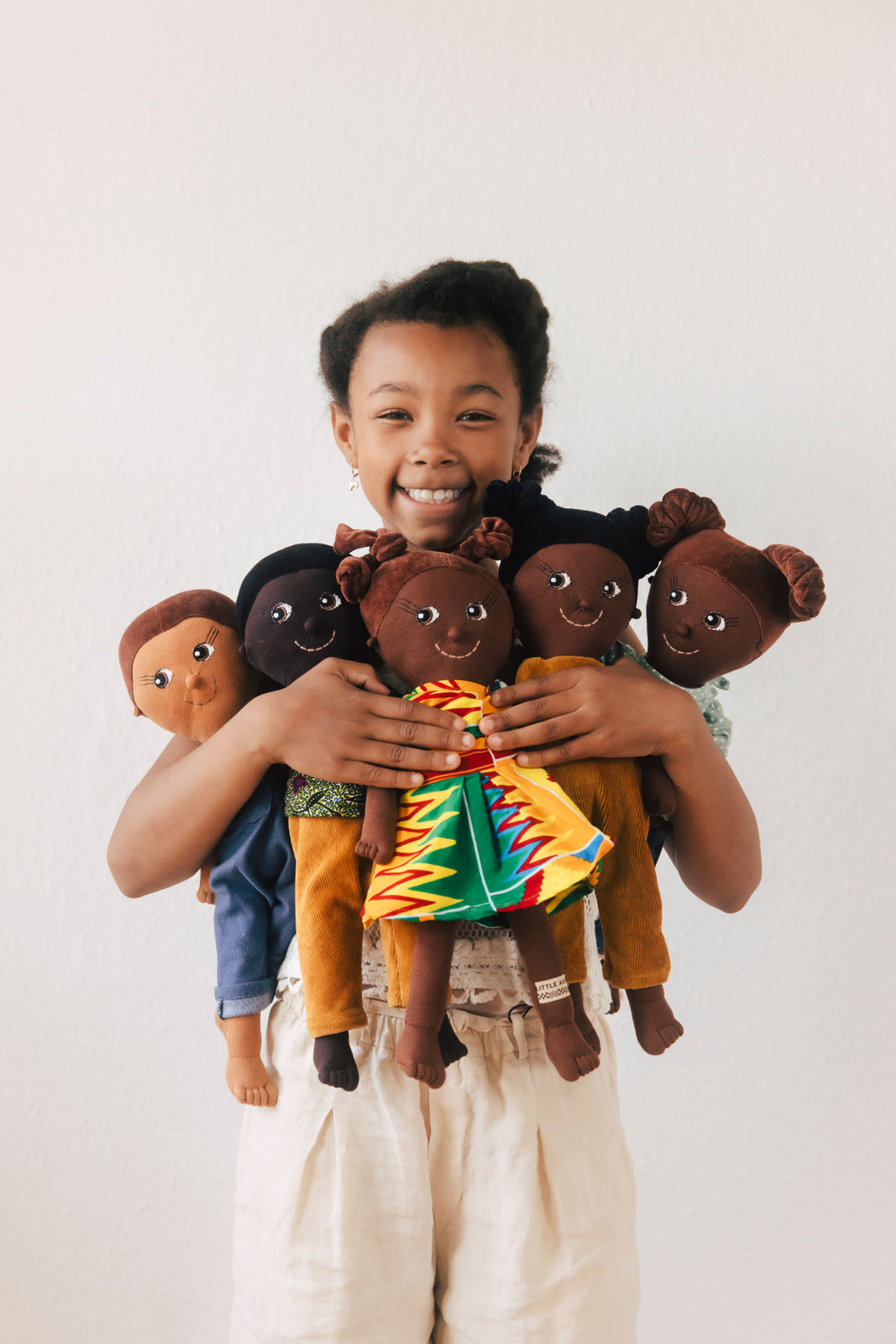 Ein schwarzes Mädchen hält eine Auswahl an Diversity-Puppen von LITTLE ASHÉ in den Händen