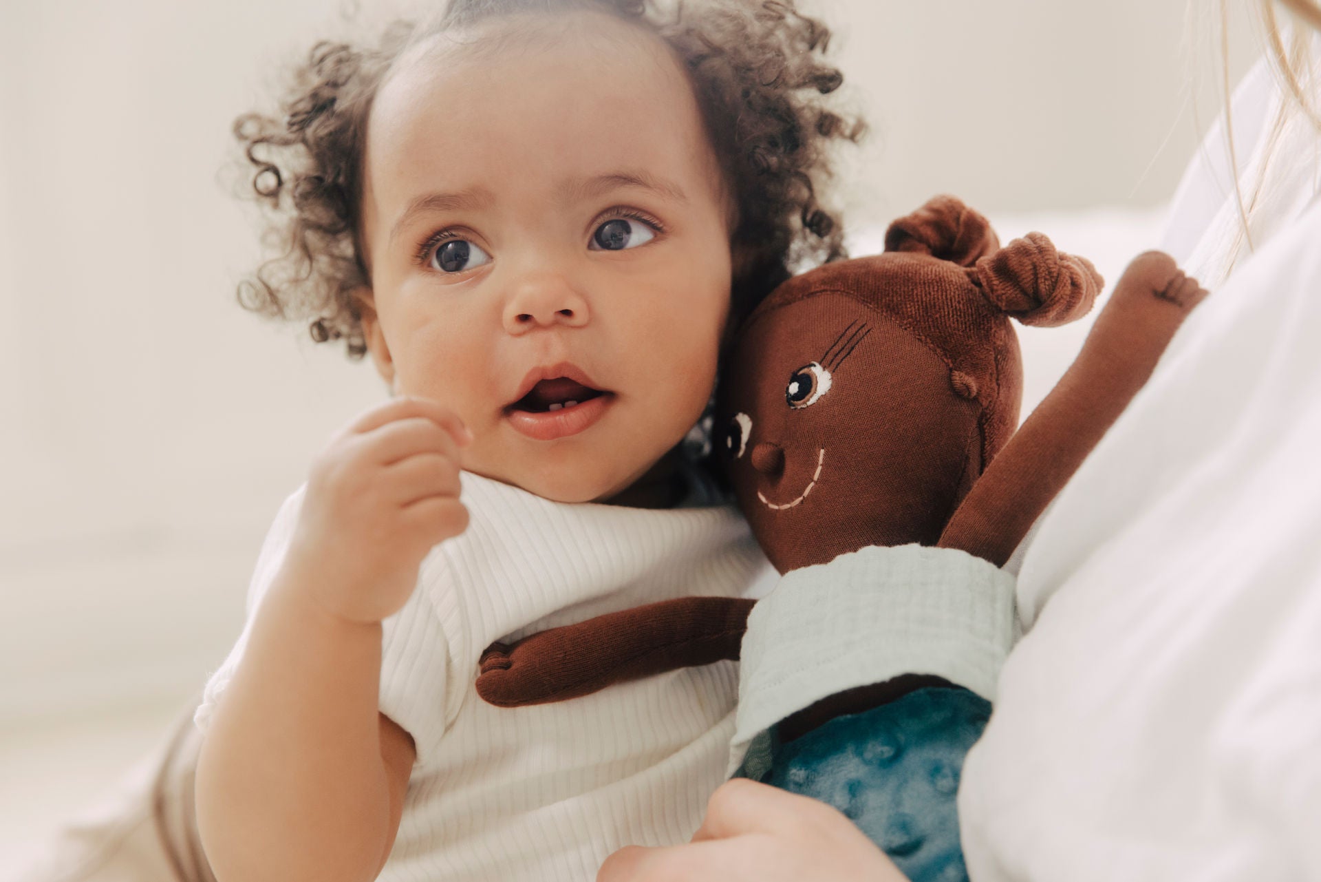 Ein Baby schmust mit weicher schwarzer Kuschelpuppe von LITTLE ASHE