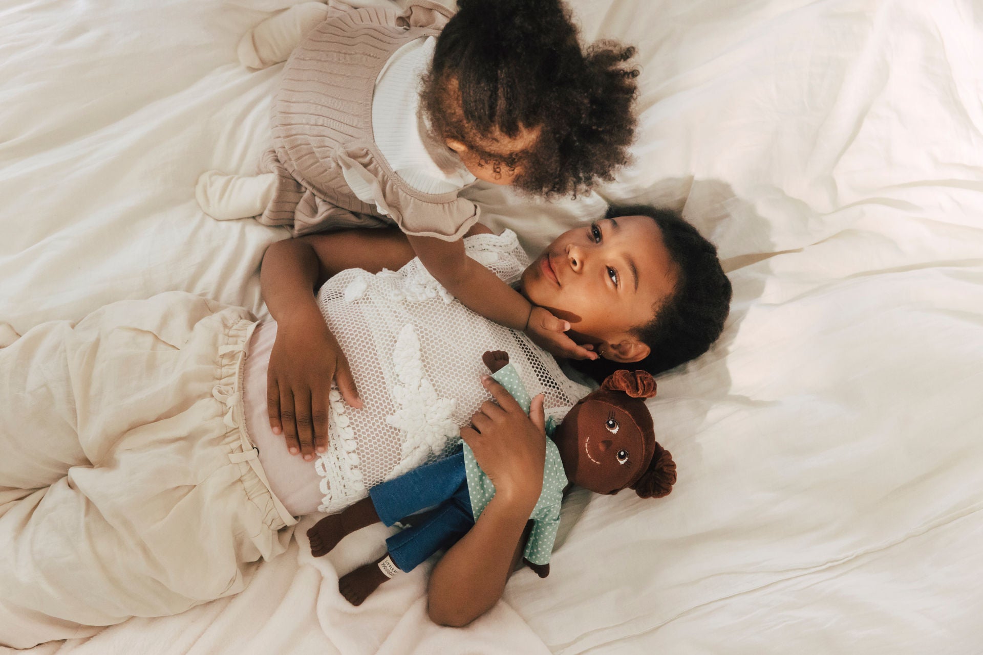 Ein Baby und ein Kleinkind spielen mit einer handgemachten Diversity-Puppe von LITTLE ASHÉ